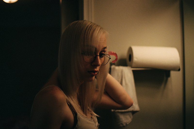 A person with glasses and light hair in warm indoor light.