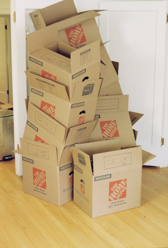 A tall stack of moving boxes beside a white door.