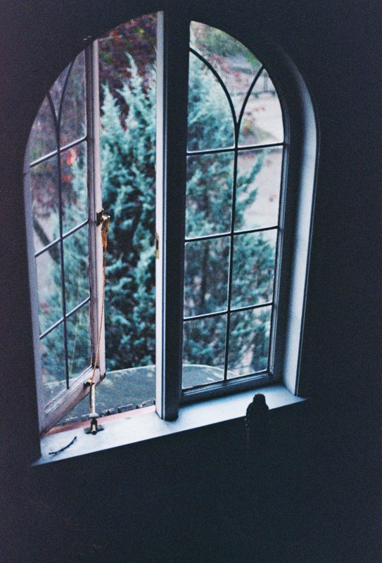 An arched window and its sill against a shadowed wall.