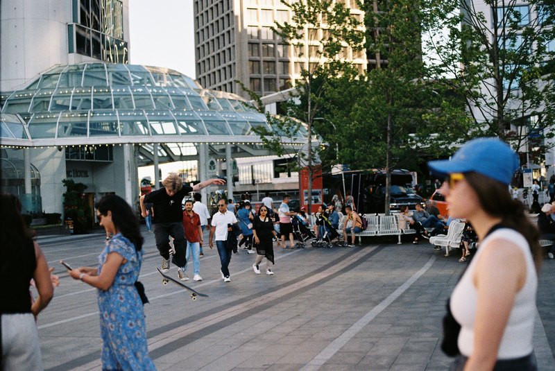 A skateboarder mid-jump among pedestrians in a city plaza.